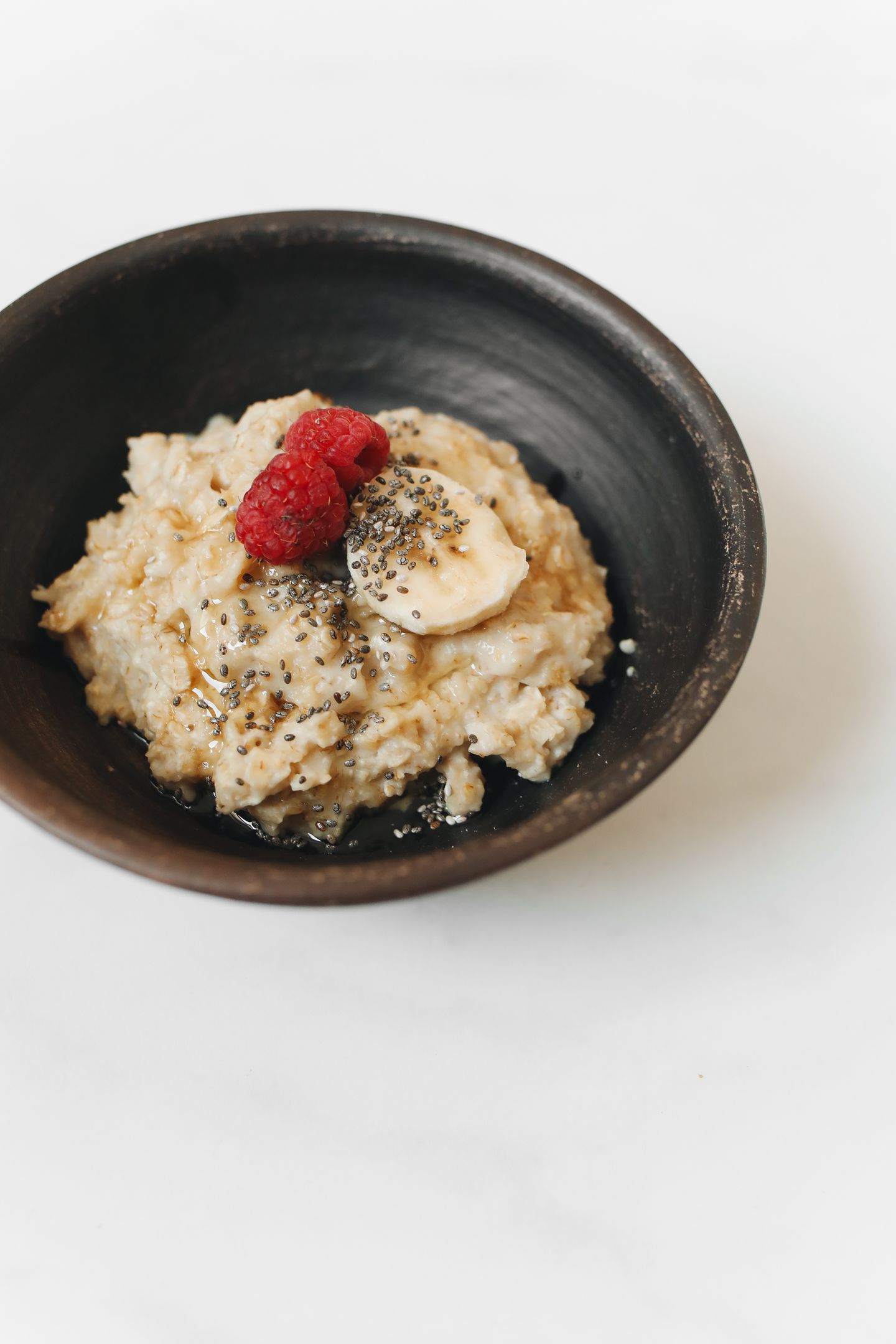 Delicious and nutritious oatmeal topped with banana, raspberries, and chia seeds.